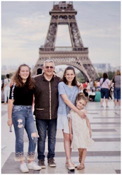A happy family posing in front of the iconic Eiffel Tower in Paris, France.
